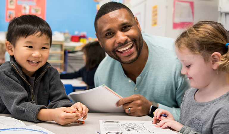 Teacher with students learning from worksheets