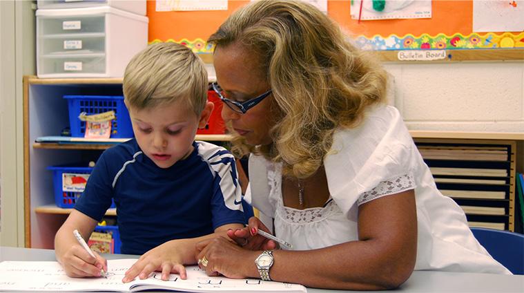 Teacher helping a student with handwriting, illustrating the principles of Learning Without Tears.